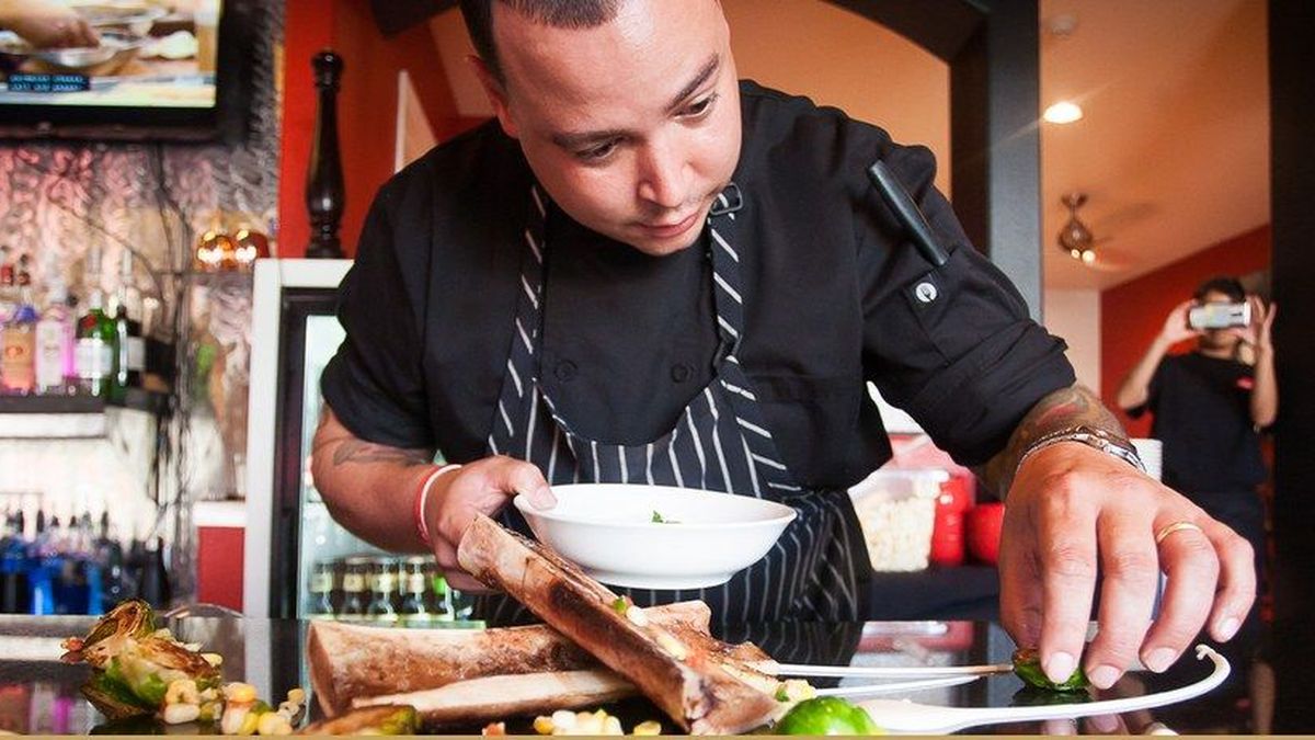 A chef plating a dish at a restaurant pass